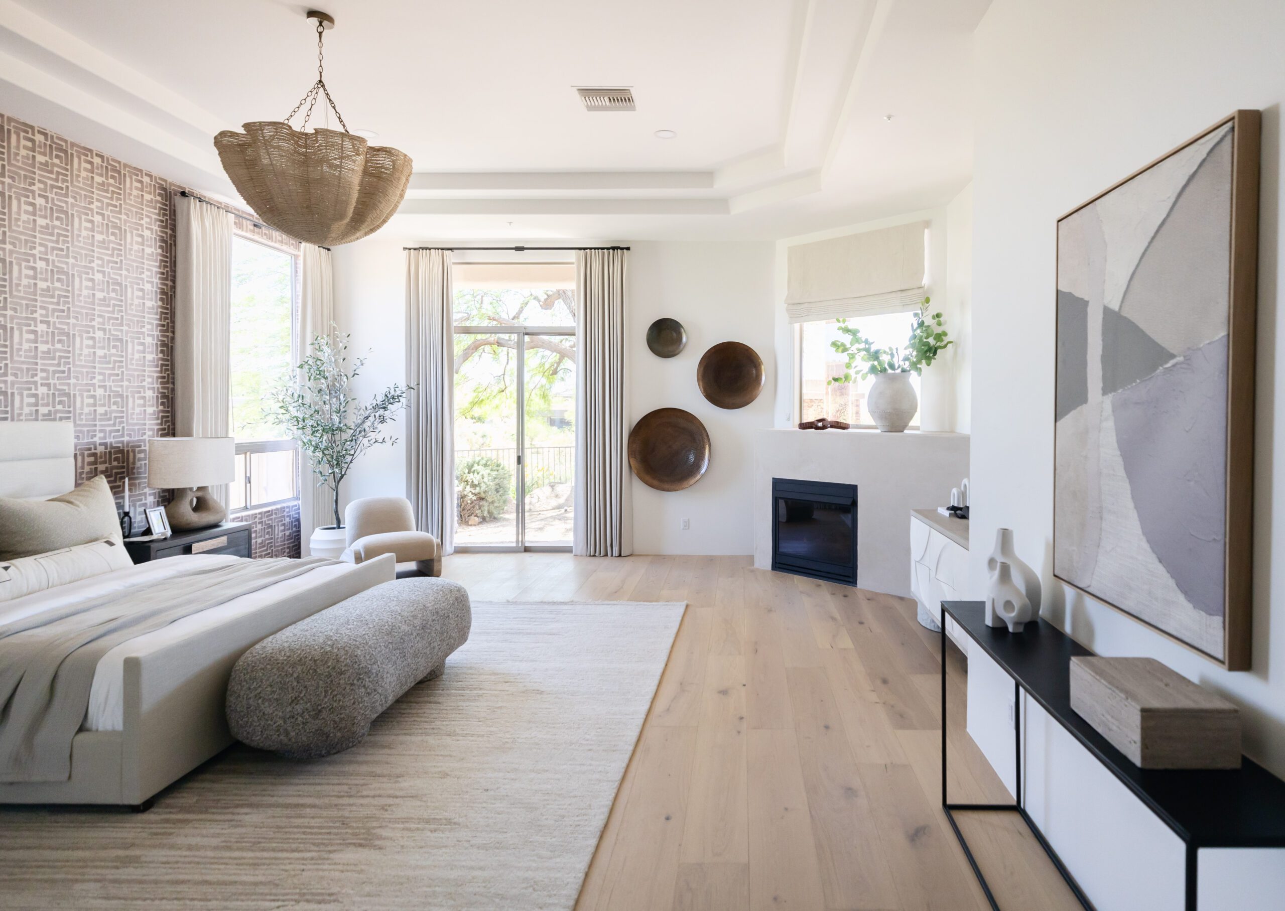 Desert-toned primary suite with a rounded plaster fireplace and woven pendant light, Lolo Prestige Property, Scottsdale interior design by Living with Lolo