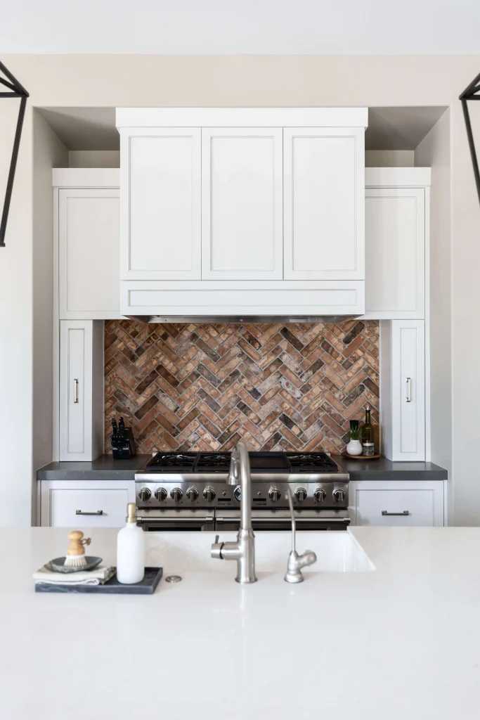 Kitchen stove with brick backsplash and white cabinets