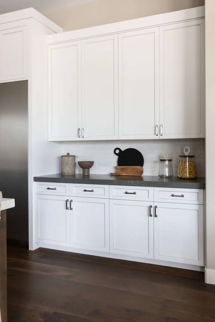 Clean white kitchen cabinets with dark countertop and decorative jars
