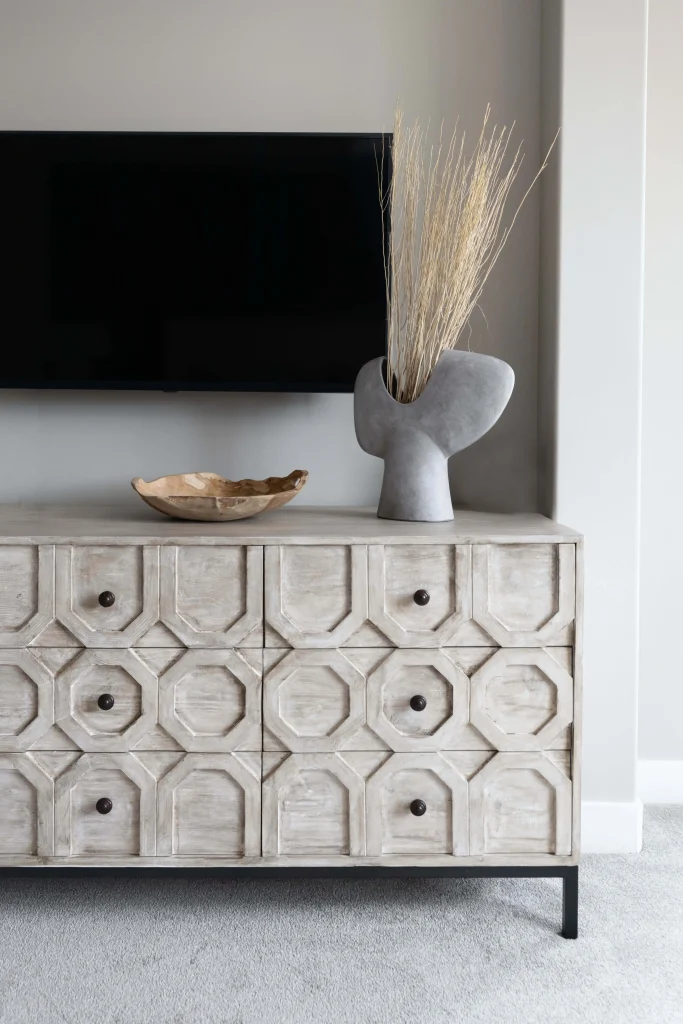 Decorative wooden sideboard with geometric patterns, modern vase, and TV