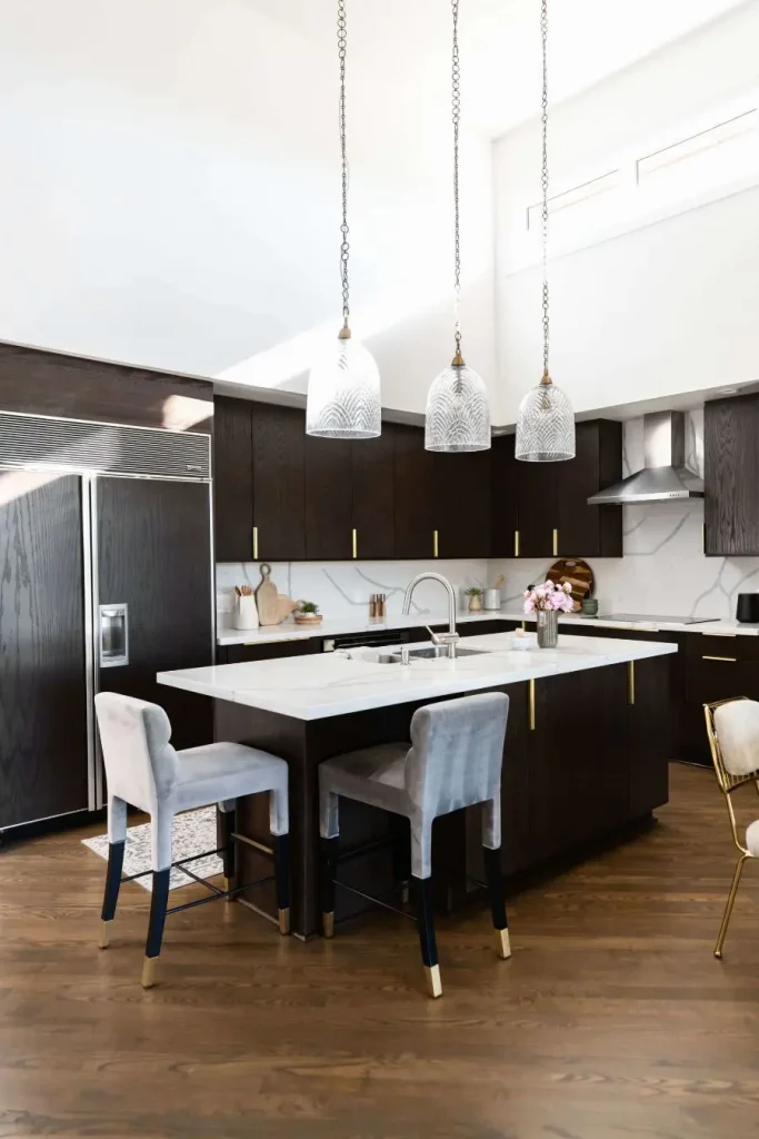 Modern kitchen featuring dark wood cabinets, white marble island, pendant lights, and gray bar stools