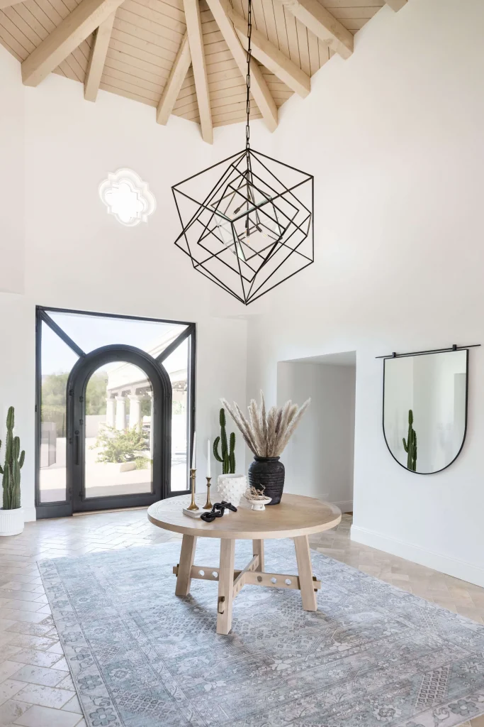 Bright entryway with geometric light and natural wood table