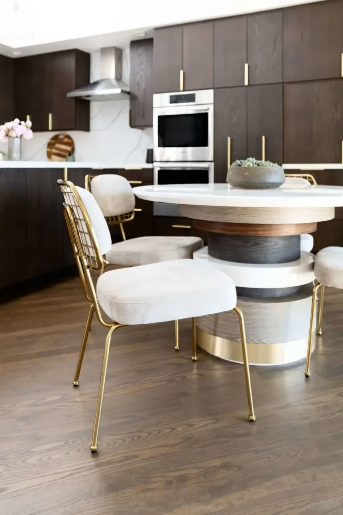 Modern kitchen with gold chairs and round white table.