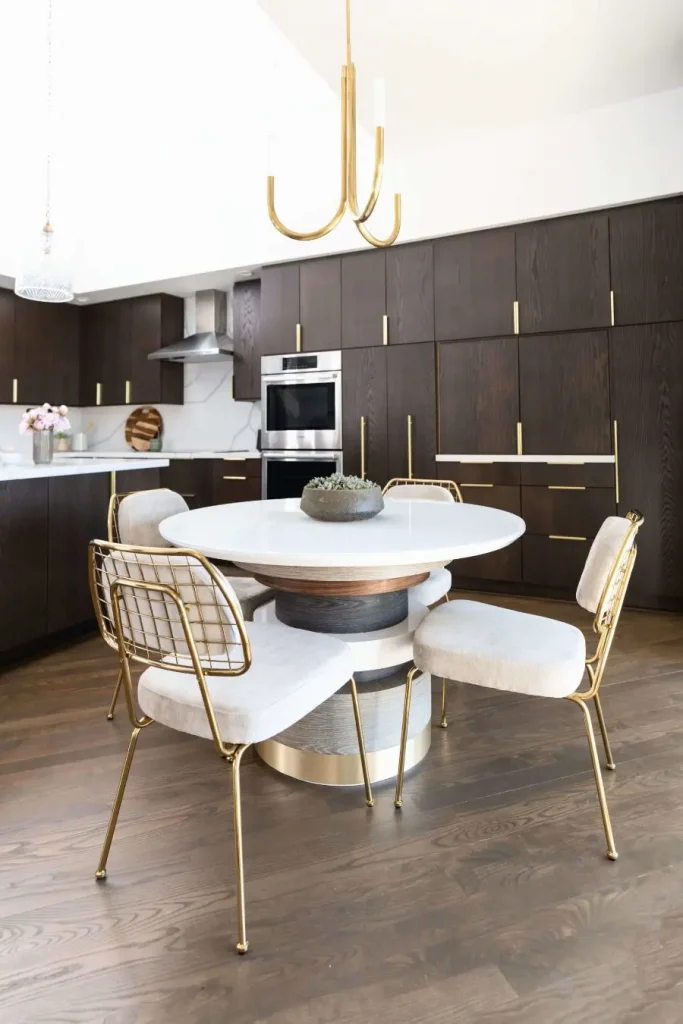 Contemporary kitchen with dark wood cabinets, white round table, and gold-accented chairs