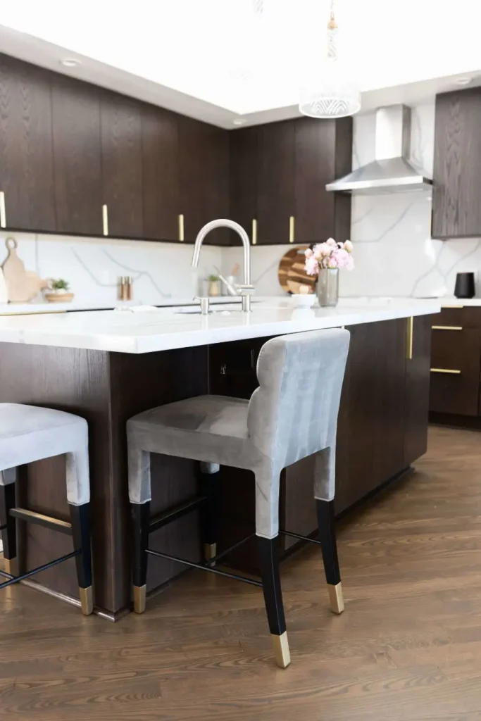 Modern kitchen island with dark wood cabinetry and gray upholstered bar stools