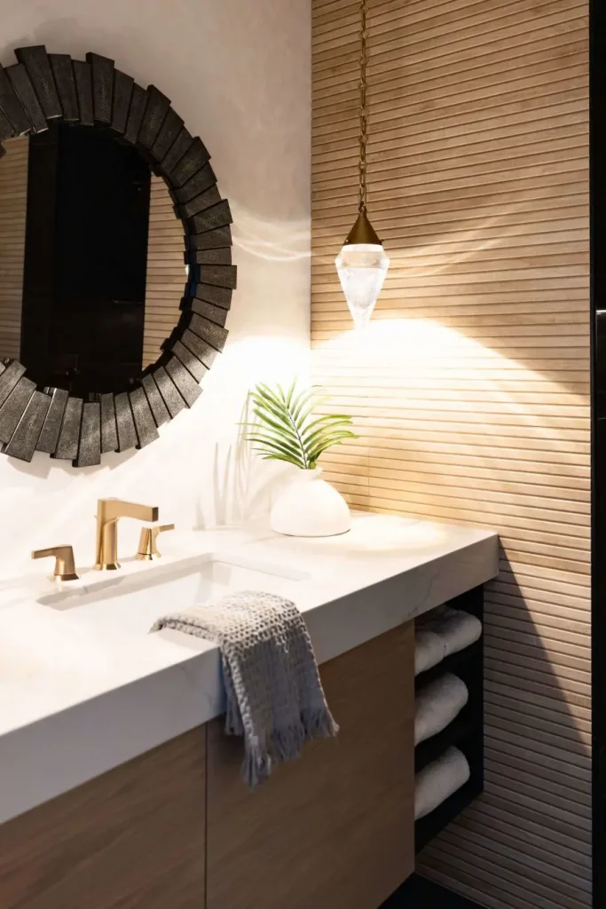 Modern bathroom vanity with a white countertop, gold faucet, black textured round mirror
