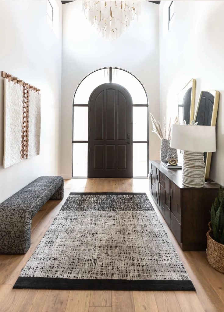 Double-height entry with arched door and neutral decor