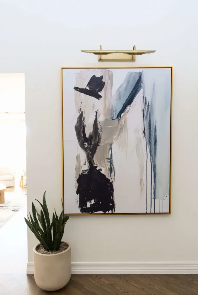 Abstract painting with black, gray, and blue strokes above potted snake plant