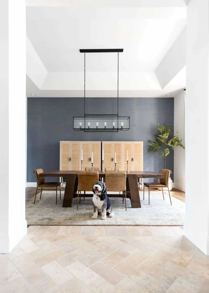 Dining room with wooden table, tan chairs, and dog