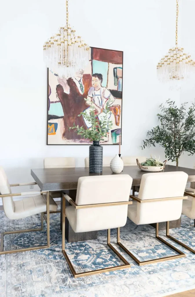 Dining table with beige chairs and two gold chandeliers above