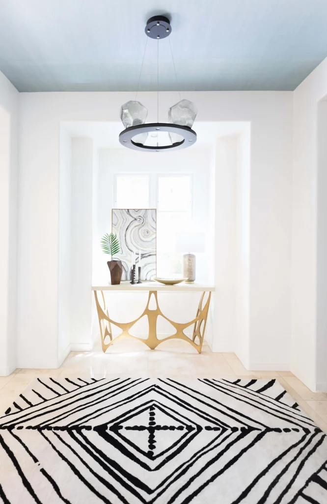 Bright hallway with geometric black and white rug and gold-accented console table