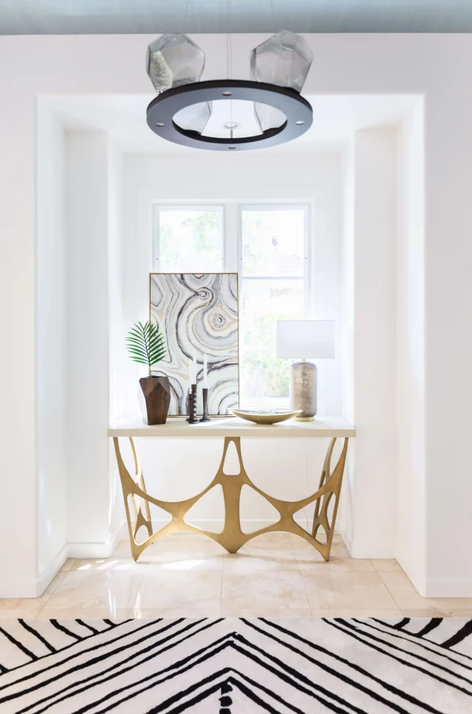 Stylish hallway with black-and-white geometric rug and gold metal console table