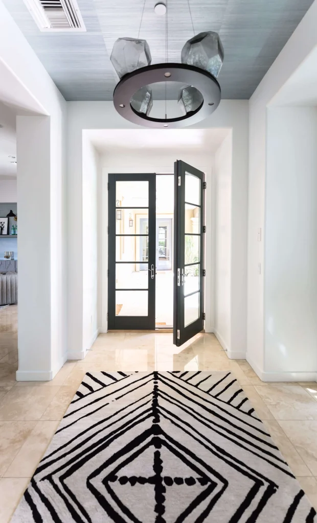 Entrance hallway with black double doors and black-and-white geometric rug