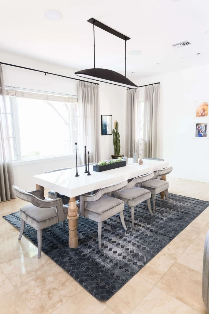 Elegant dining area with white table, gray velvet chairs, and large windows