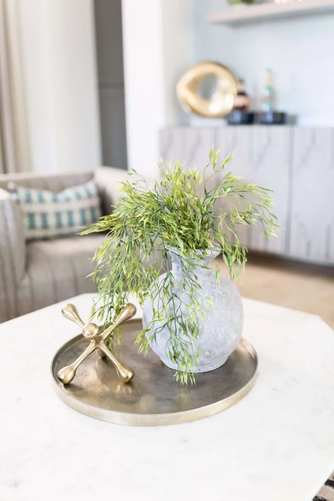 Stone vase with greenery and gold accent on marble table
