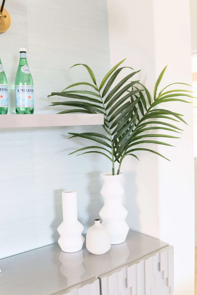White geometric vases with green palm leaves on glossy cabinet