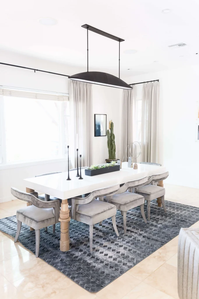 Bright dining room with white table, gray chairs, and black pendant light