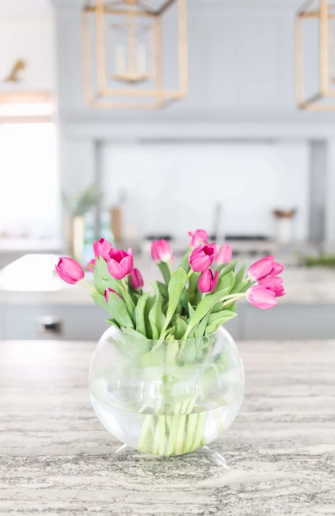 Kitchen with pink tulips in a clear glass vase on marble countertop