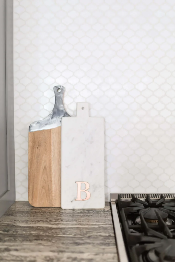 Two cutting boards leaning against a tiled backsplash next to a stovetop