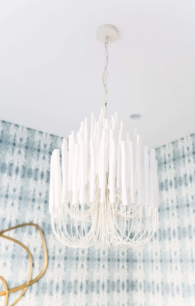 Close-up of a white chandelier with vertical candle-like rods hanging from the ceiling