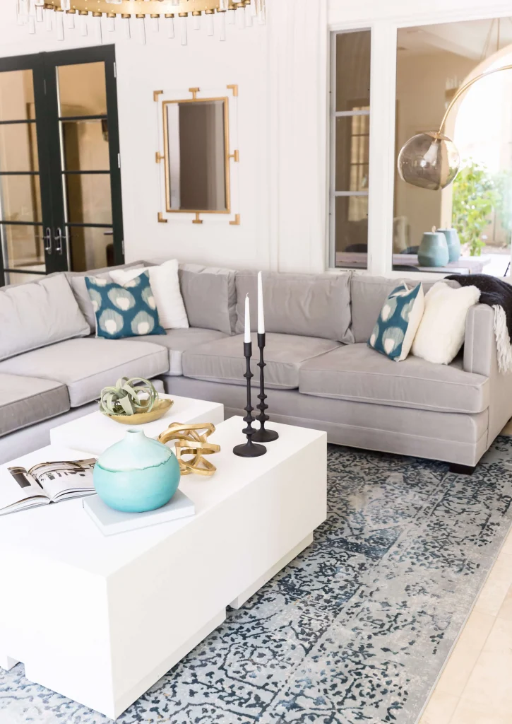 Gray sectional sofa with blue and white pillows and white coffee table with decor