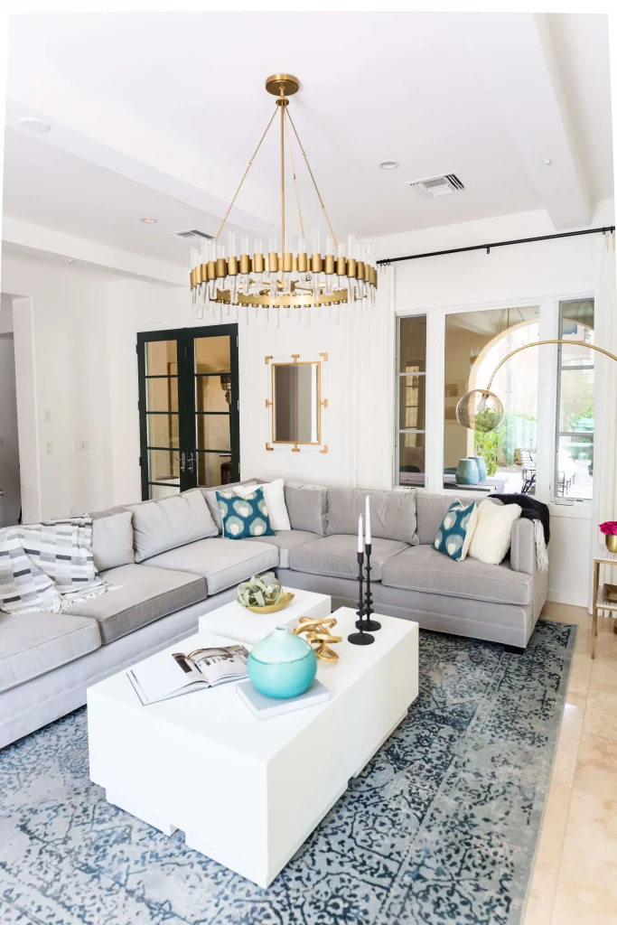 Modern living room with gray sectional sofa, white coffee table, and gold chandelier