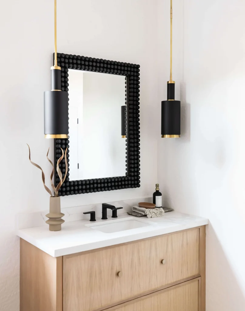 Close-up of wood vanity with black mirror and pendant lights