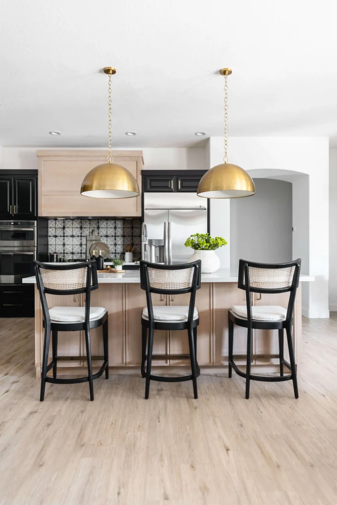 Modern kitchen with black chairs and golden pendant lights