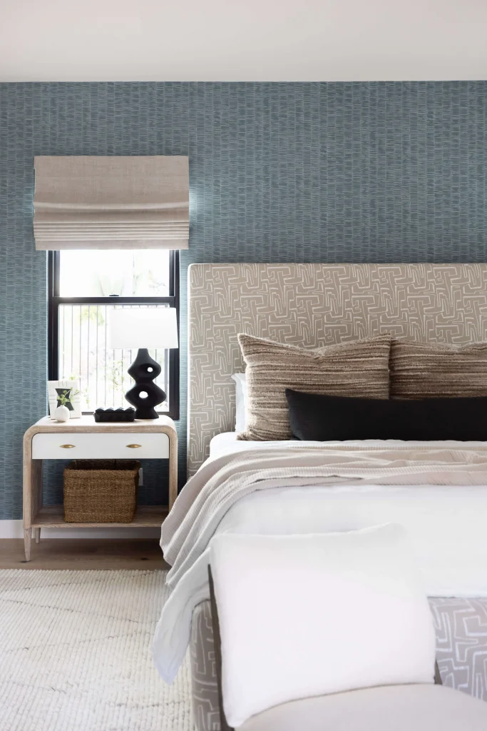 Bedroom with blue textured wall, neutral bedding and side table