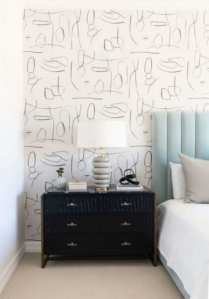 Black bedside table with lamp and abstract wallpaper