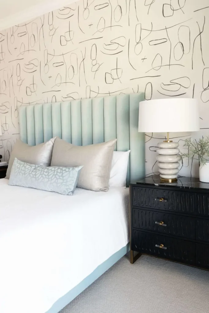Elegant bedroom with blue tufted headboard and black nightstand