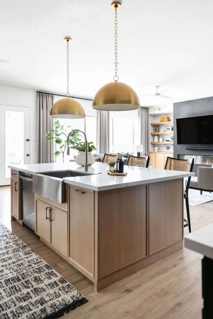 Kitchen with large island, brass pendant lights, and open living space