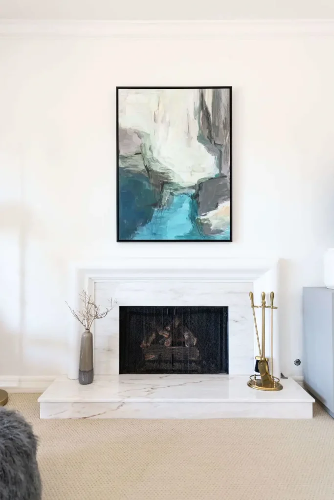 White marble fireplace with abstract painting above and decorative items