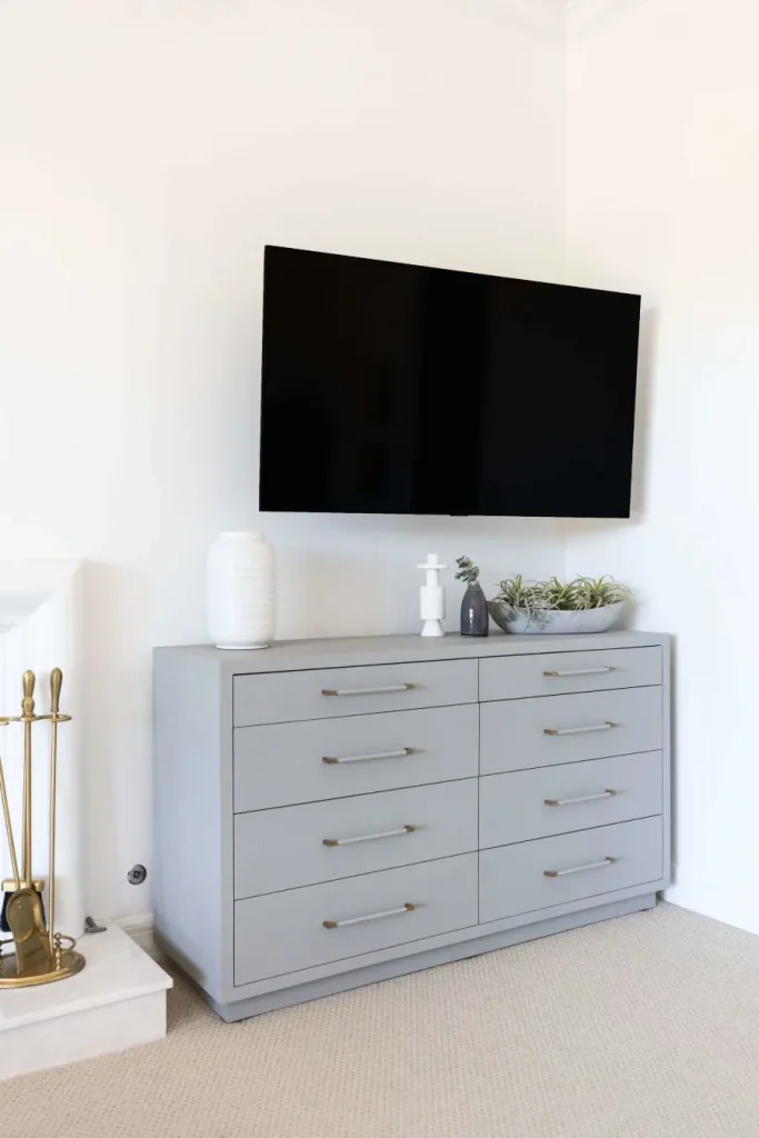 Wall-mounted TV above gray dresser with modern decor