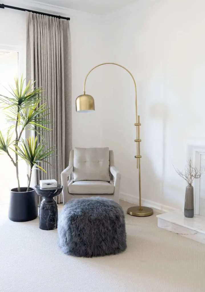 Cozy reading nook with gold lamp and gray ottoman