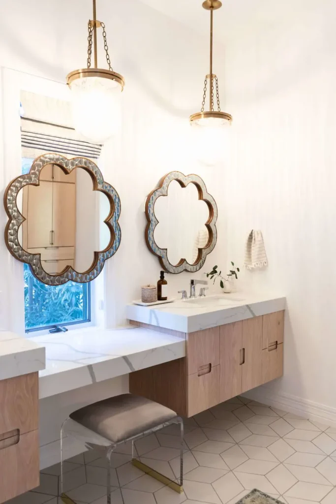 Light wood vanity with white marble countertop and decorative mirrors