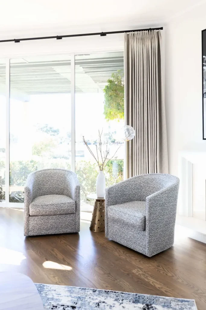Pair of gray and white patterned barrel chairs in front of large sliding glass door