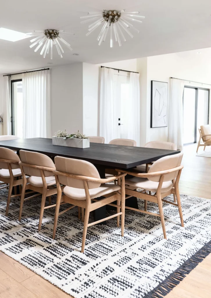 Contemporary dining room with long black table and rug