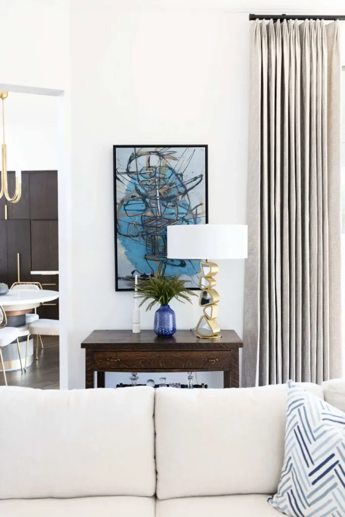 Living room corner with sculptural lamp, dark wood table, and bold blue painting.