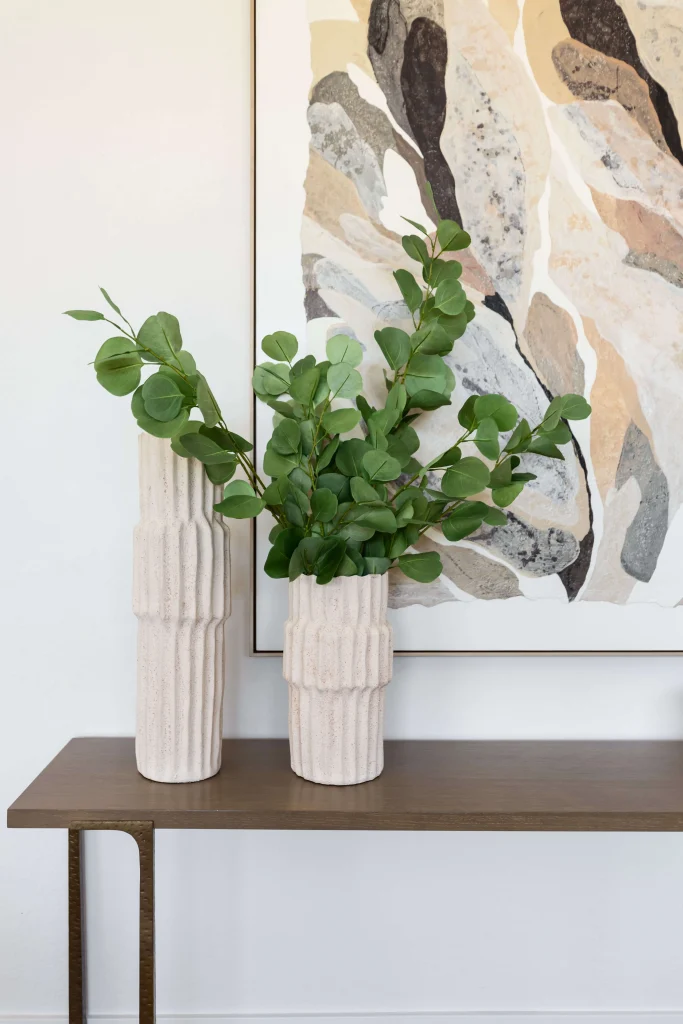 Textured vases with green leaves on table