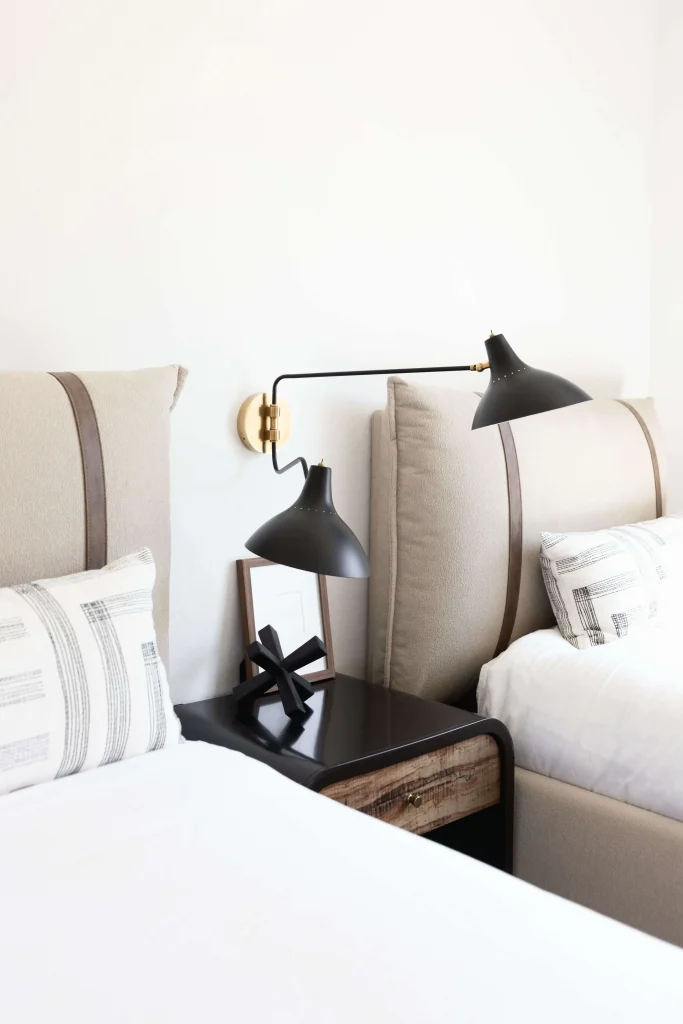 Beige beds with black wall-mounted lamps