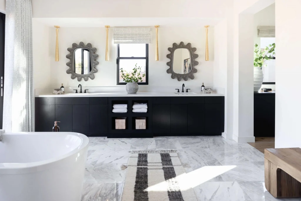 Bathroom with marble floors, black cabinets, and double mirrors