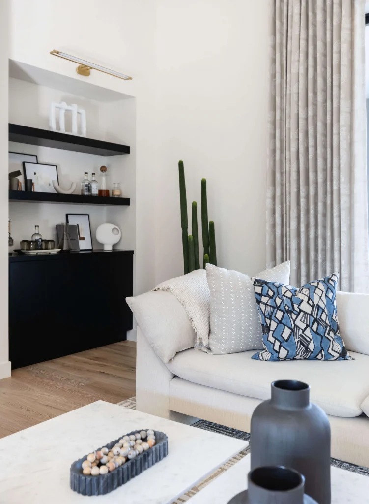 Minimalist seating area with white sofa, tall cactus, and floating shelves