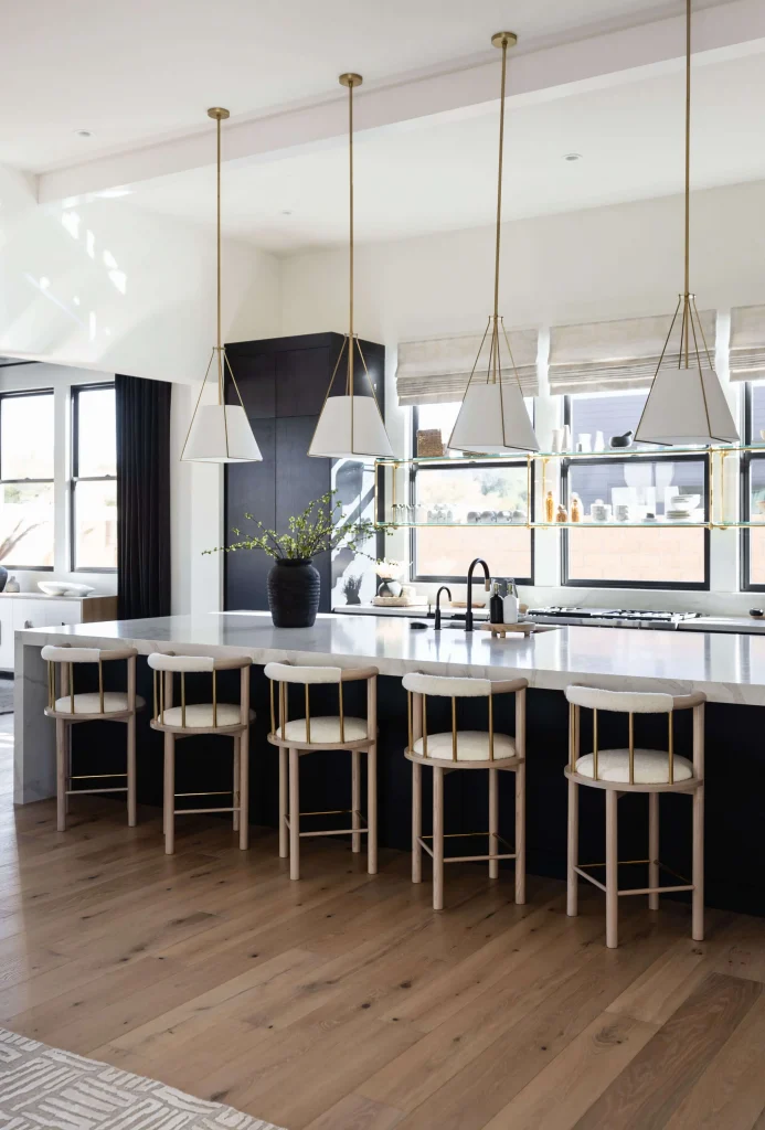Bright kitchen with marble island, brass pendant lighting, and wood flooring