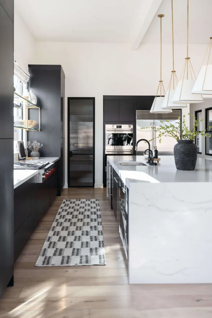 Modern black and white kitchen with marble island and gold lighting