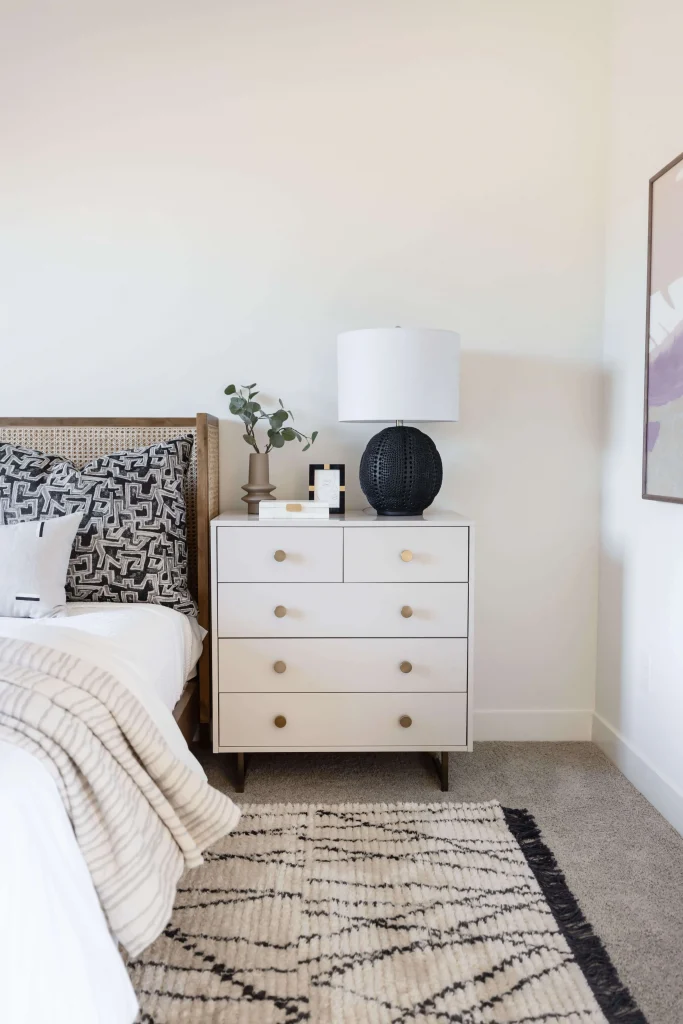 Cozy bedroom with white nightstand, black lamp, and patterned bedding