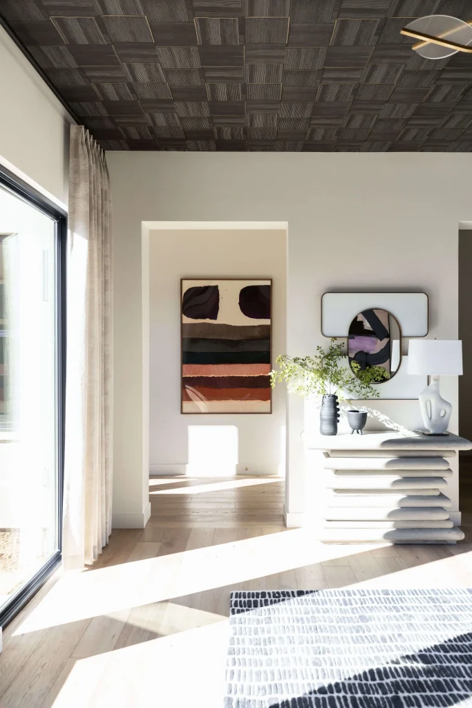 Sunlit room corner with stacked console table, artwork, and decorative mirror
