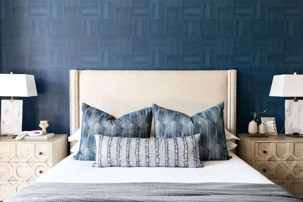 Beige bed with blue pillows and wooden nightstands