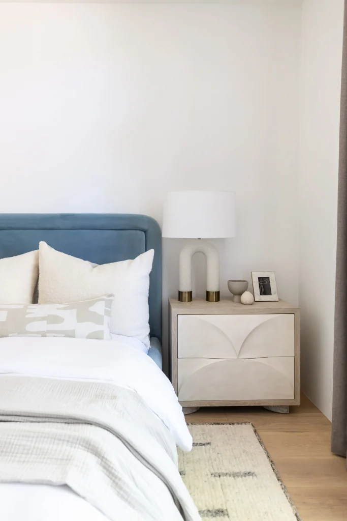 Bedroom with blue upholstered headboard and white bedding