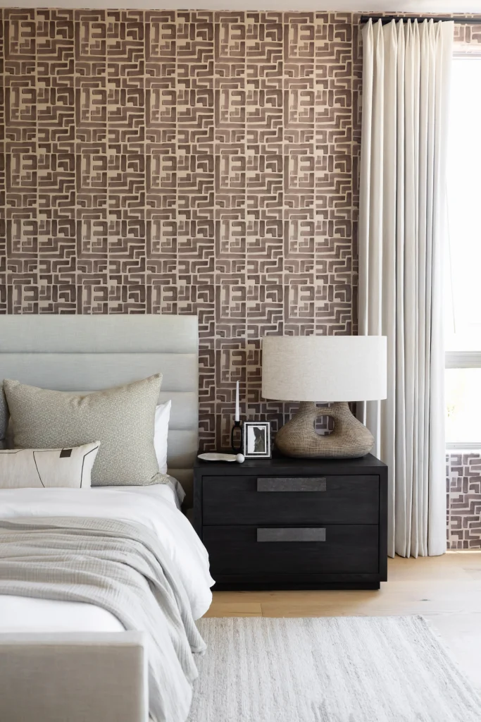 Bedroom with patterned wallpaper and gray upholstered bed